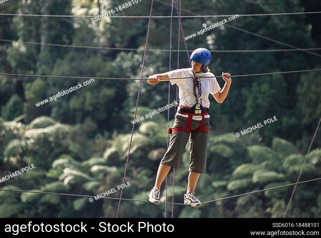 Woman manoeuvring along suspended ropes on outdoor ropes course
