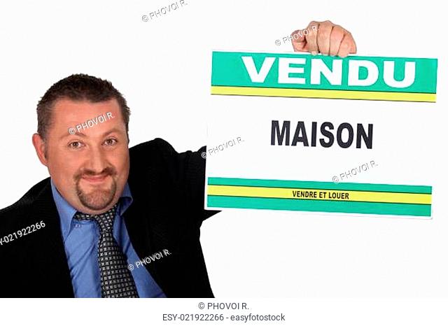 Estate agent holding a 'Vendu' sign