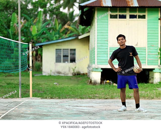 A young man standing and holding a rattan ball that is used in the sport Sepak takraw, a type of kick volleyball native to the Malay-Thai Peninsula