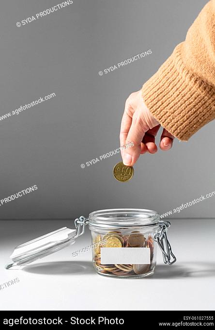 hand putting coin into jar and making donation