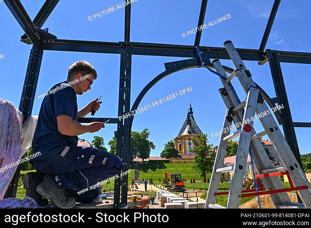 31 May 2021, Brandenburg, Neuzelle: An employee of the company Gußer Metallbau GmbH erects a pavilion in the extension of the monastery garden