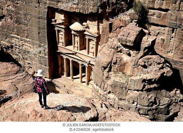 Woman watching the famous and elaborately carved façade of Al Khazneh (the Treasury), carved out of a sandstone rock face