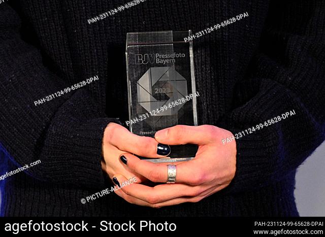 24 November 2023, Bavaria, Munich: Lorenz Mehrlich, photographer and winner of the Press Photo of the Year 2023, holds his award in his hands after the ""Press...