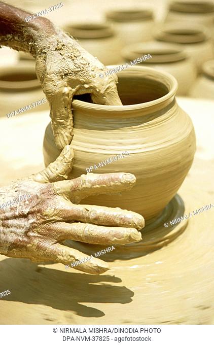 Pottery ; traditional Indian kumbhar ( potter ) hands giving shape to Clay pot ; uttar pradesh ; india