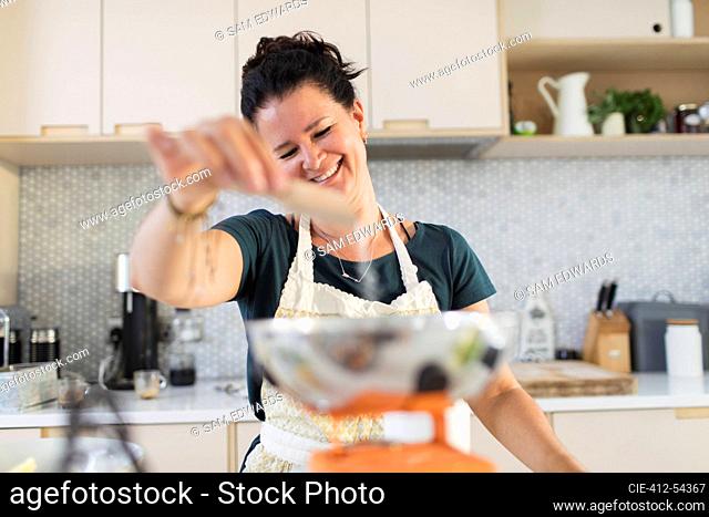 Smiling woman using baking scale in kitchen