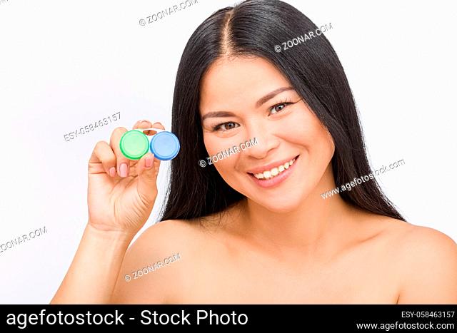 Happy Korean or Asian woman holding container for contact lenses isolated on white background in studio. Vision, beauty concepts
