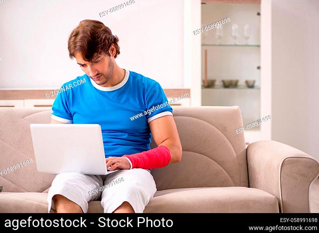 Young man with injured arm sitting on the sofa