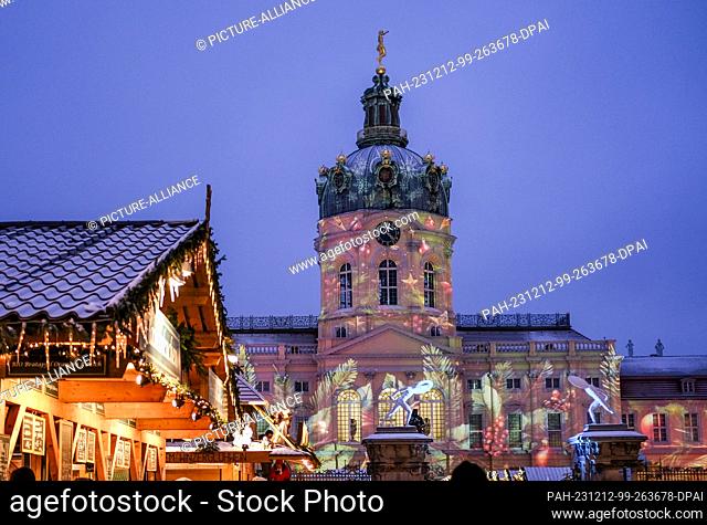 03 December 2023, Berlin: The Christmas market at Charlottenburg Palace and the palace façade are atmospherically illuminated in the evening at dusk