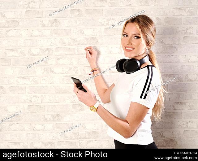 Beautiful young woman with cheerful fitness skating and consulting mobile phone