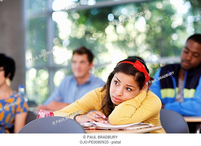 Student resting head on desk in classroom