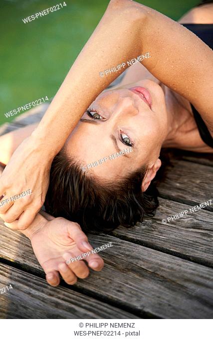 Portait of mature woman lying on a jetty at a lake