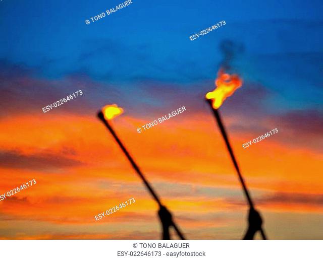 Fire torch at sunset sky with red clouds