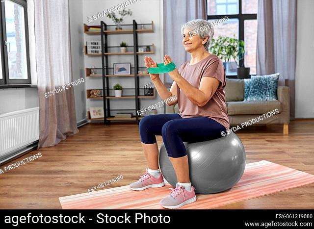 senior woman exercising with elastic band at home