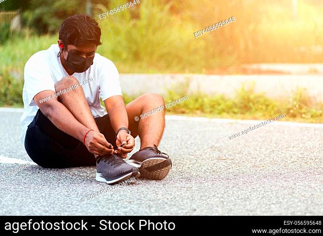 Close up Asian sport runner black man wear watch sitting he trying shoelace running shoes getting ready for jogging and run outdoor street health park with copy...