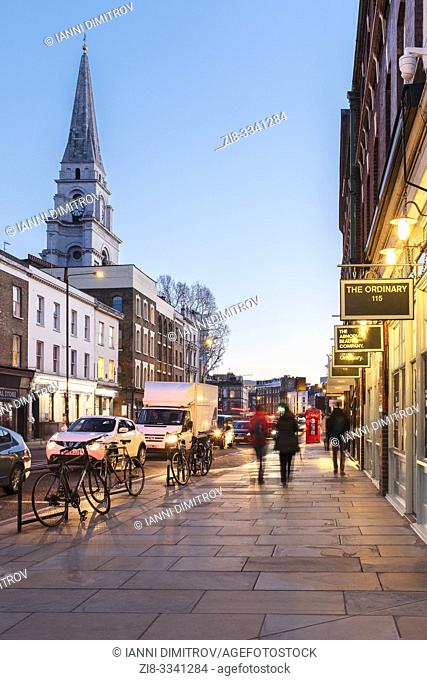 Brushfield Street, with designer shops on the South side of Spitalfieds Market and Christ Church Spitalfieds at night, London, UK