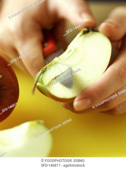 An apple being cored, on yellow chopping board