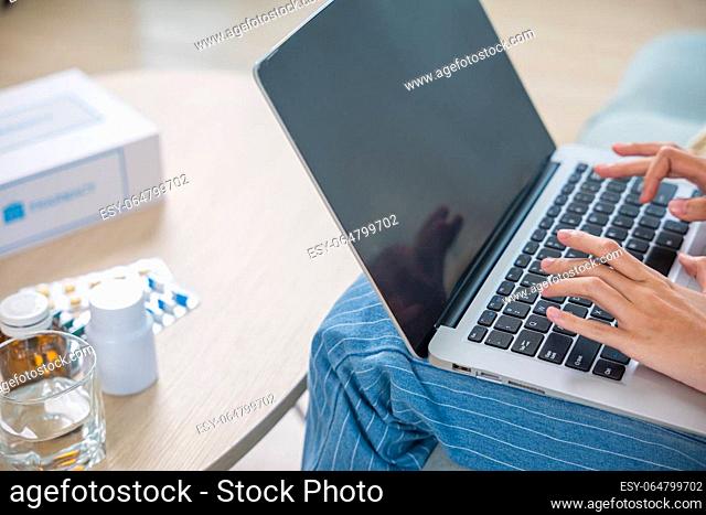 Business female sick she taking pills for flu while work with laptop keyboard, Asian sick woman covered blanket suffering from covid-19 virus but still working...