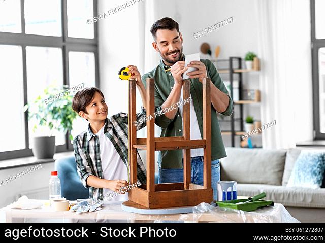 father and son with ruler measuring old table