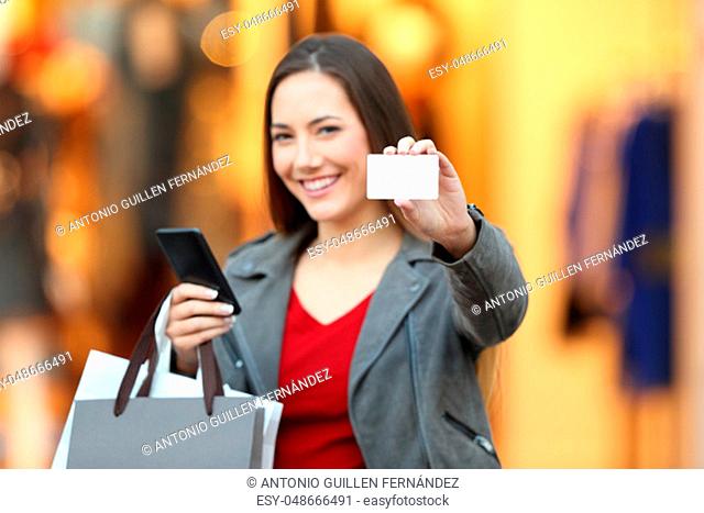 Potrait of a fashion shopper showing credit card and phone in a mall