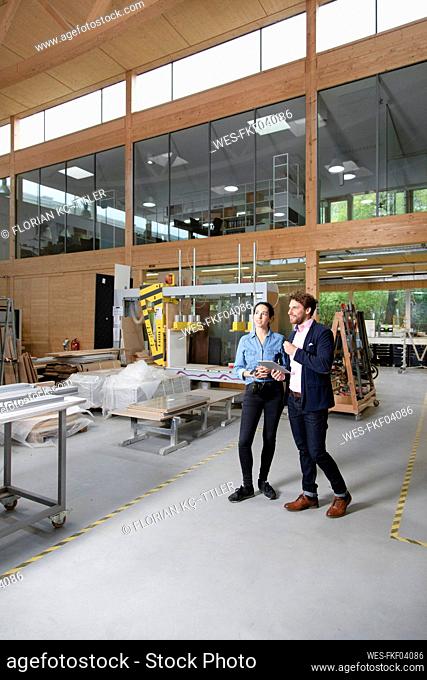 Male and female entrepreneurs discussing while standing in factory