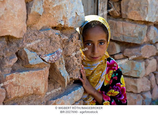 Young girl, berberine, looking curiously from behind a wall, Middle Atlas Mountains, Morocco, Africa