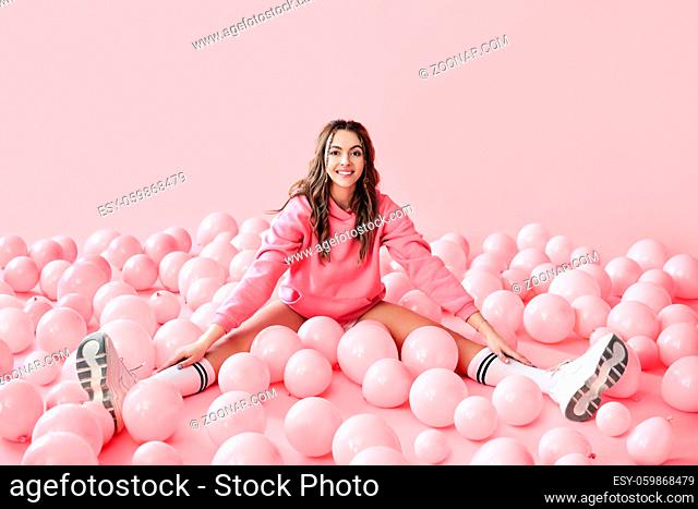 Young trendy woman posing with pink ballons on pink background. Pop art. Celebraion, festive, fun concept