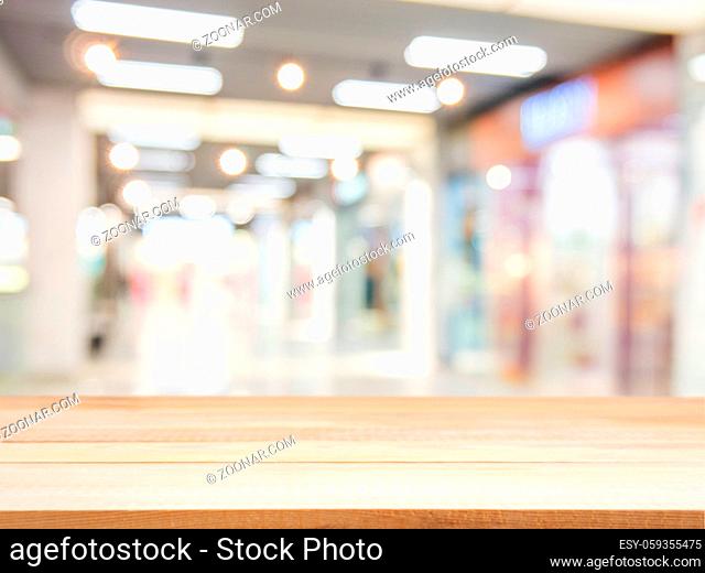 Wooden board empty table in front of blurred background. Perspective light wood over blur in shopping mall - can be used for display or montage your products
