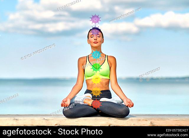 woman meditating in lotus pose with seven chakras