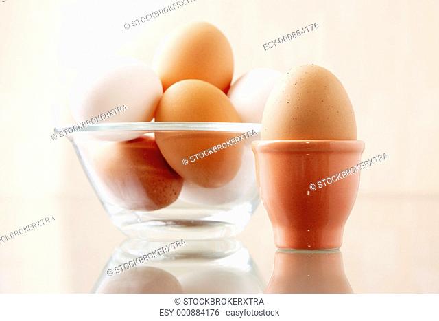 Image of fresh egg in ceramic form on background of several other ones in bowl