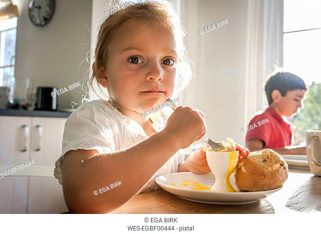 Portrait of girl eating a boiled egg at dining table