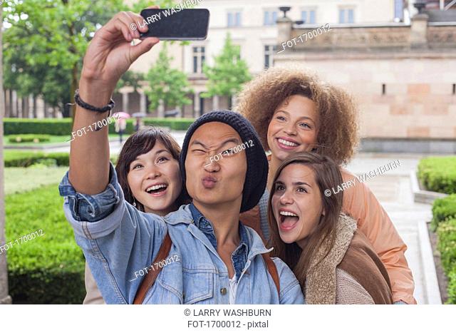 Young man making face while taking selfie with female friends, Berlin, Germany
