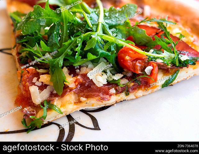 In the picture Italian pizza close-up with Arcula, cherry tomato, tomato, mozzarella, cheese, parmesan and Bresaola