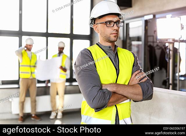 male architect in helmet and safety west at office