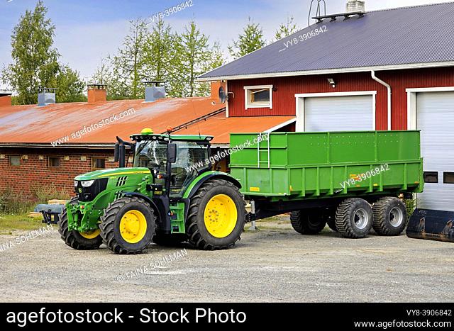 John Deere 6155R Tractor in front of Palmse 1900 trailer at the farm yard on a day of early autumn. Salo, Finland. August 29, 2020