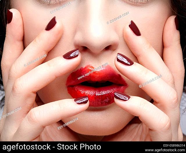 Closeup beauty portrait of young woman with hands near face. Brunette girl with unusual alyapy red female face makeup