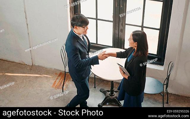 Top view happy two Asian young businessman and woman shaking hands greeting before meeting or negotiation with digital tablet sitting on desk cafe