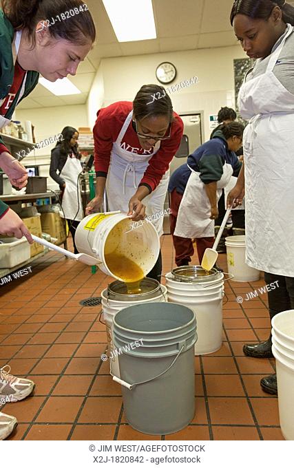 Detroit, Michigan - Volunteers filter honey they've extracted from honeycombs at Earthworks Urban Farm, a program of the Capuchin Soup Kitchen