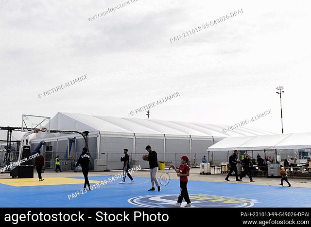 11 October 2023, Berlin: Children and young people play on the sports field in the outdoor area of the accommodation for refugees at the arrival center in Tegel