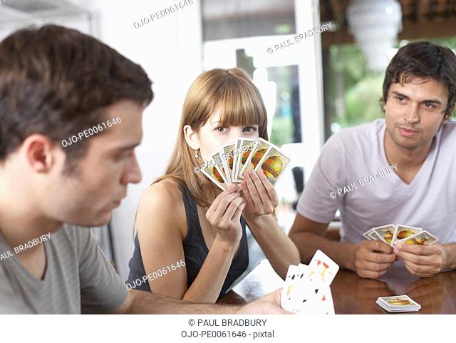 Three people playing cards at table