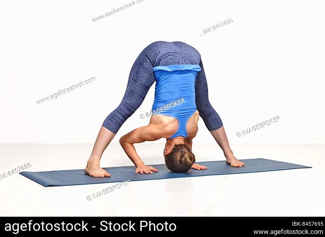 Beautiful sporty fit woman practices Ashtanga Vinyasa yoga asana Prasarita padottanasana B, wide legged forward bend B