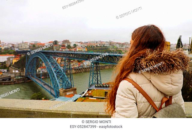 Rear view of young backpacker woman enjoying Porto sight in winter time, Portugal