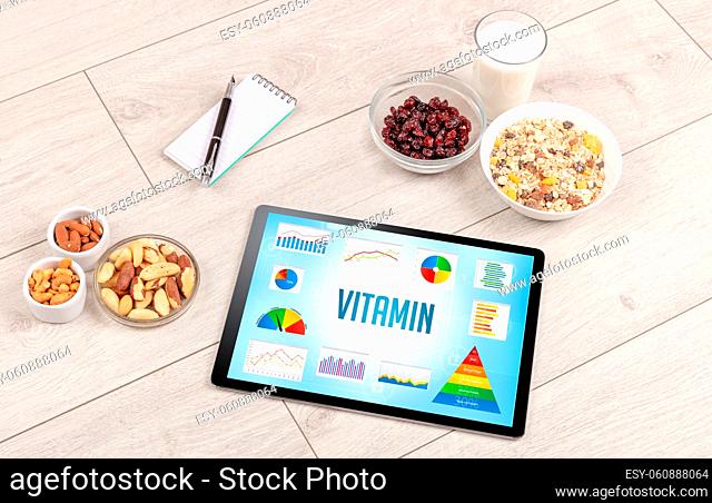 Organic food and tablet pc showing VITAMIN inscription, healthy nutrition composition