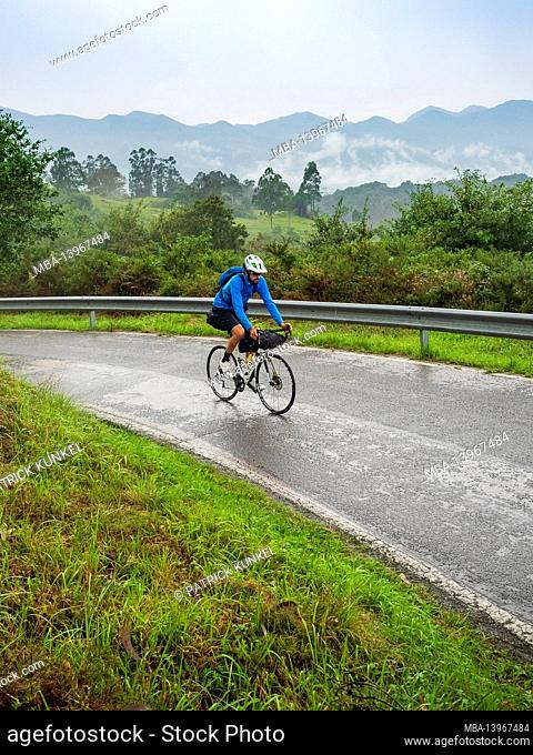 Road bike tour with luggage, bikepacking on a lonely coastal road in Asturias, Northern Spain