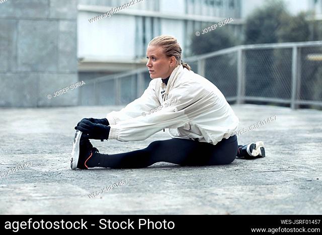 Young female athlete doing stretching exercise at park