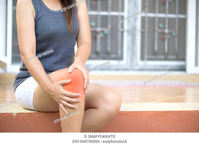 Closeup young woman feeling pain in her knee at home. Healthcare and medical concept
