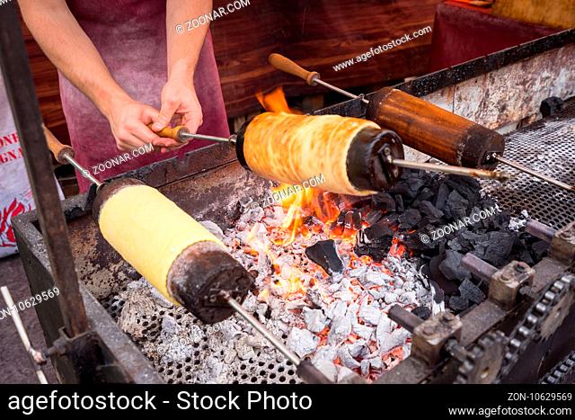 Kurtos kalacs or Chimney Cakes roll spinning over hot coals at a market stand, the typical sweet of Budapest, Hungary