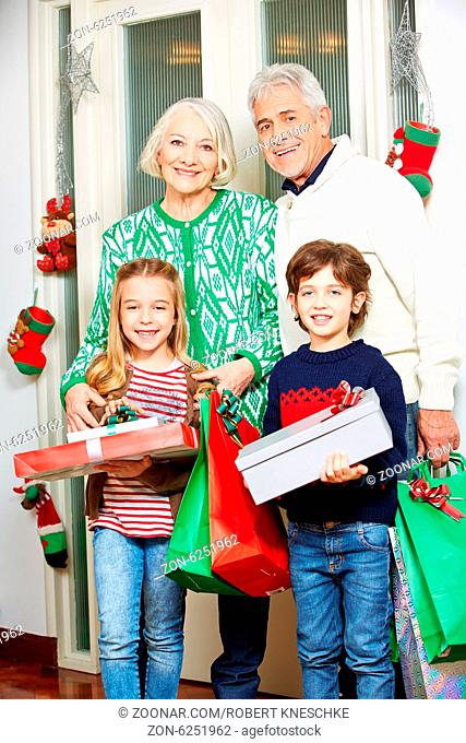 Glückliche Großeltern und ihre zwei Enkel mit Geschenken an Weihnachten