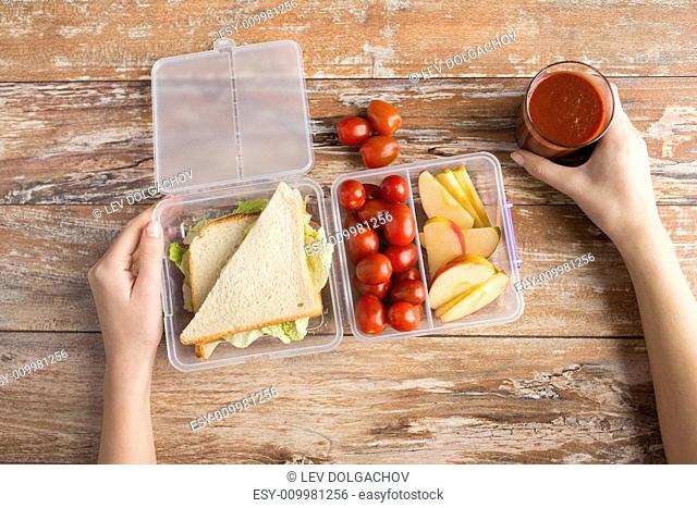 healthy eating, storage, dieting and people concept - close up of woman hands with food in plastic container at home kitchen