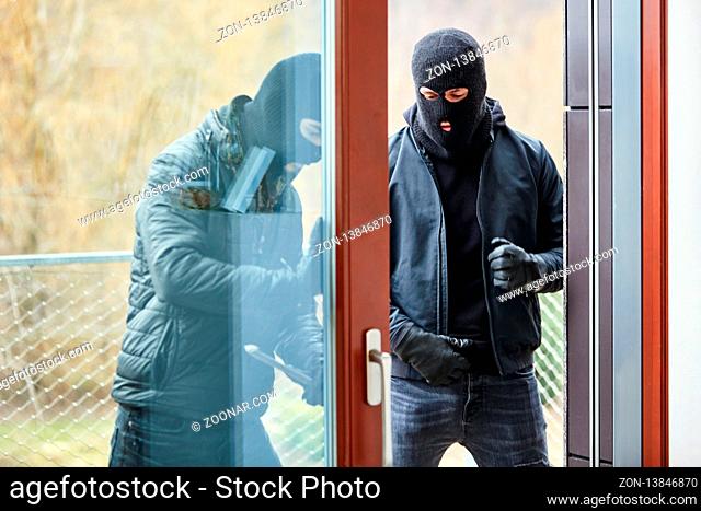 Zwei Einbrecher öffnen Terrassentür von Haus beim Einbruch mit einem Brecheisen