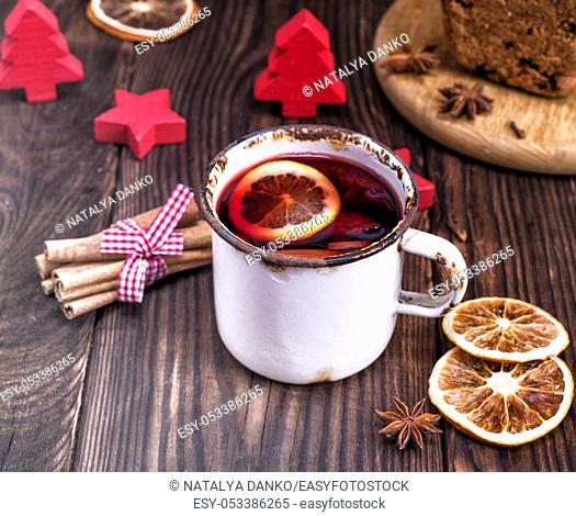 mulled wine in a white iron mug on a brown wooden table